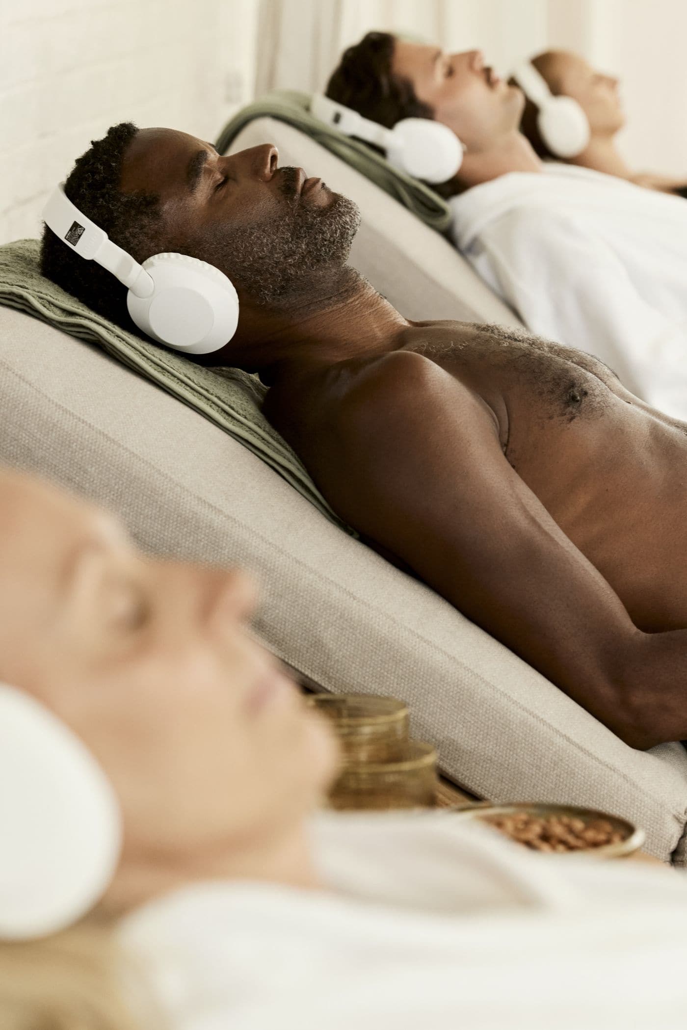 Guests reclining with headphones in the relaxation area at POND Bathhouse