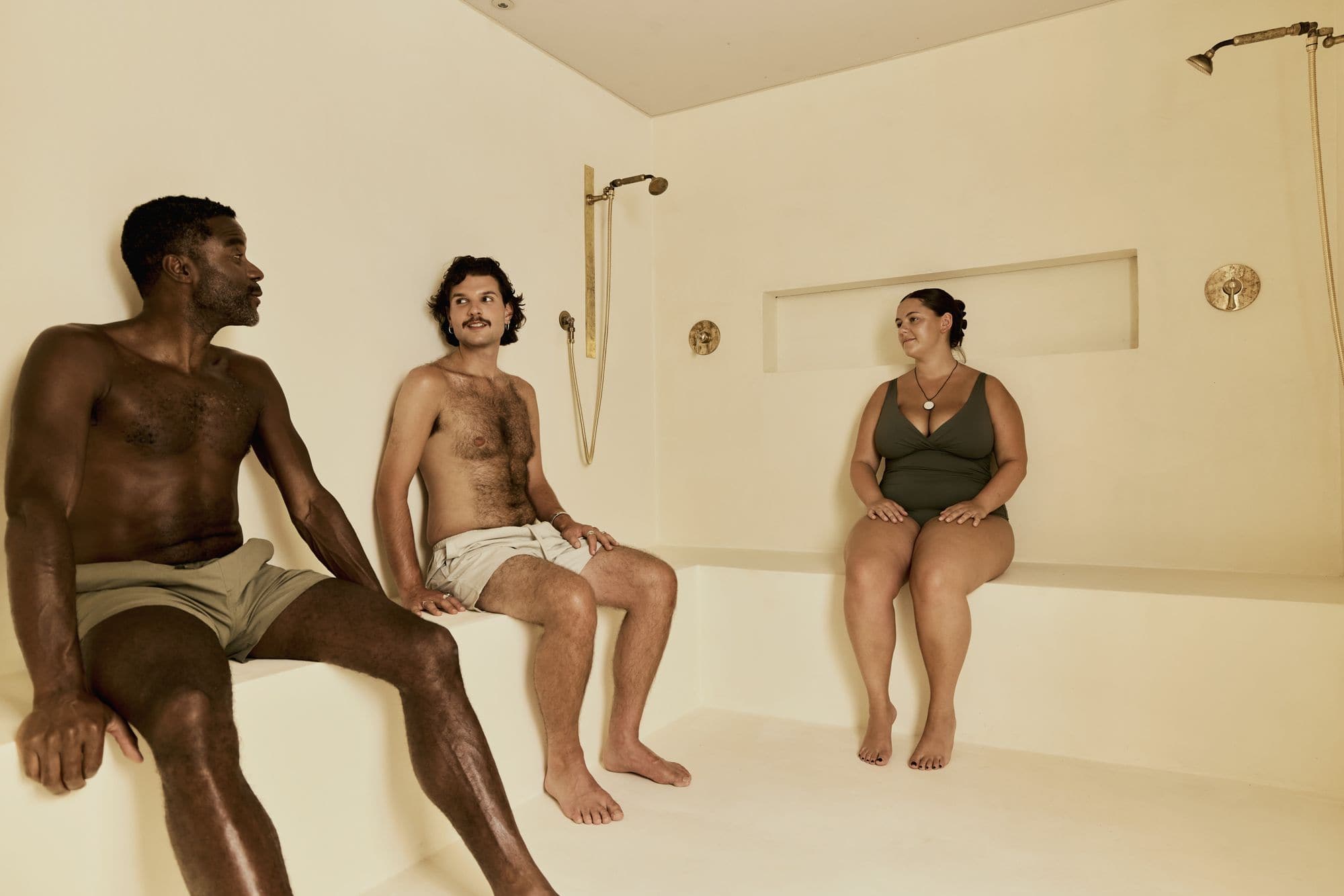 Three bathers on a stone bench in the steam room at POND Bathhouse