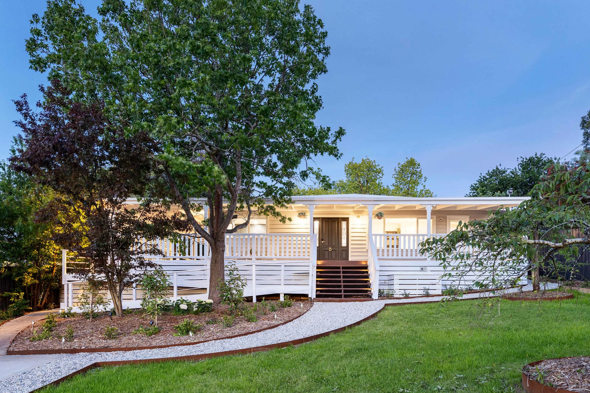 The Meadow in the evening light, a white house with a deep verandah behind a big tree