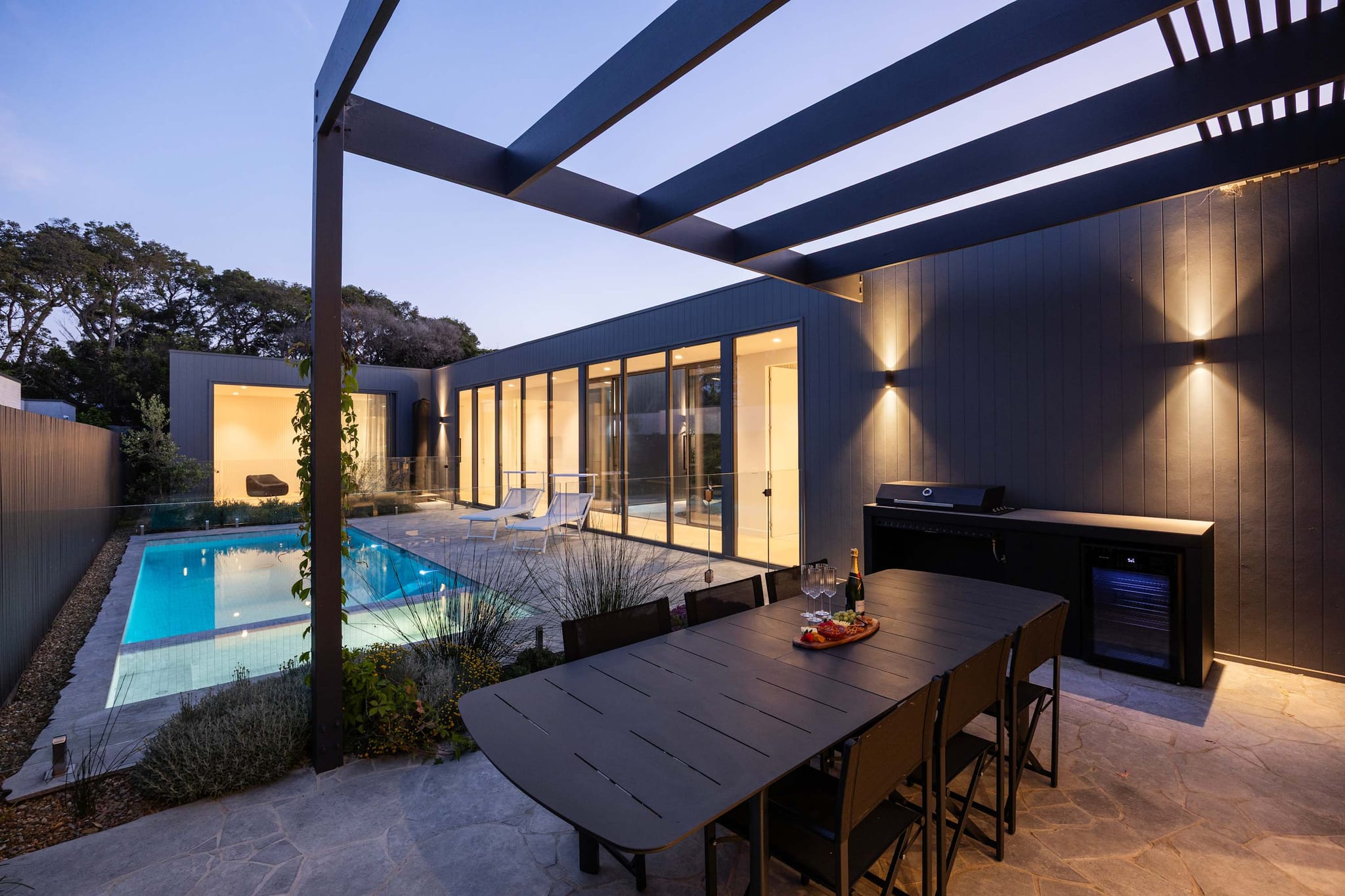 Outdoor dining table beside the pool at Atelier in Sorrento at dusk