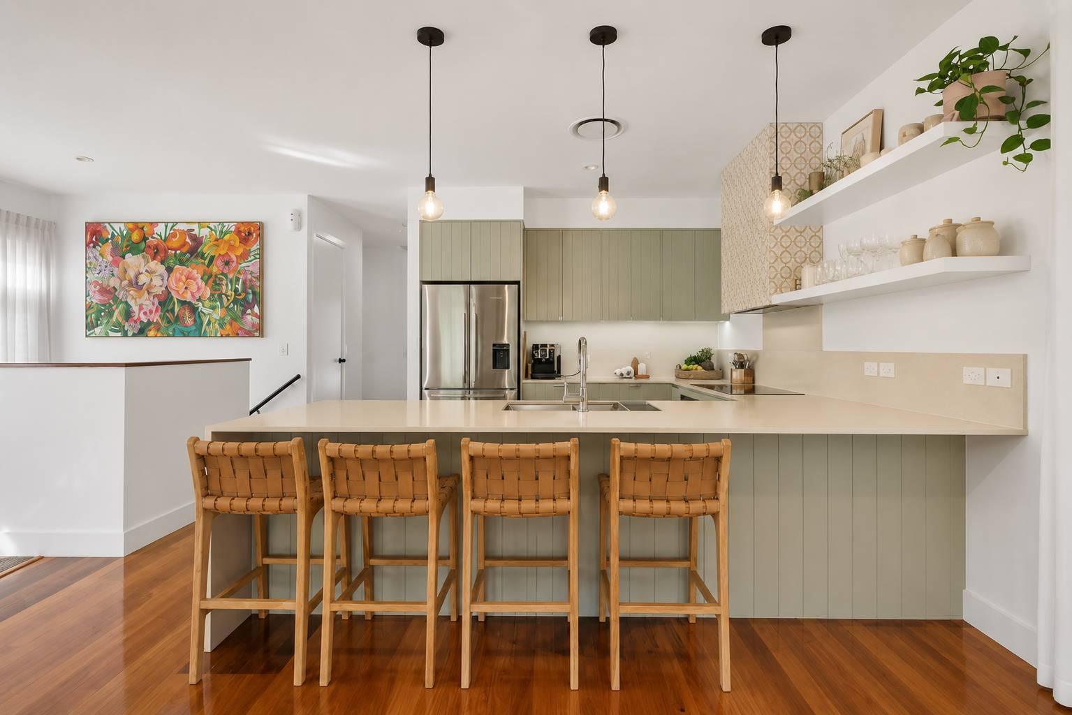 The kitchen with sage green cabinets and cane bar stools at The Beachside House, Burleigh Heads