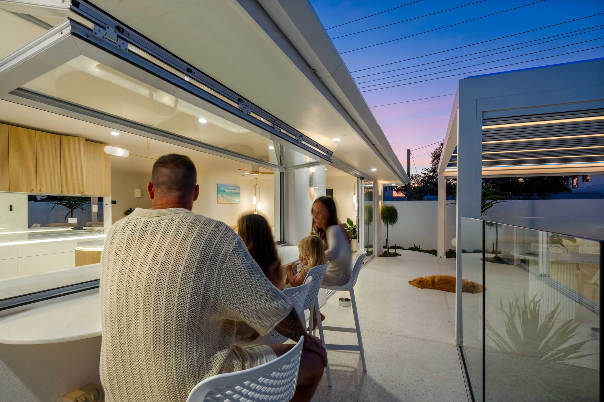 A family at the bar seats outside the kitchen's servery window at dusk, The Pavilion, Mermaid Waters