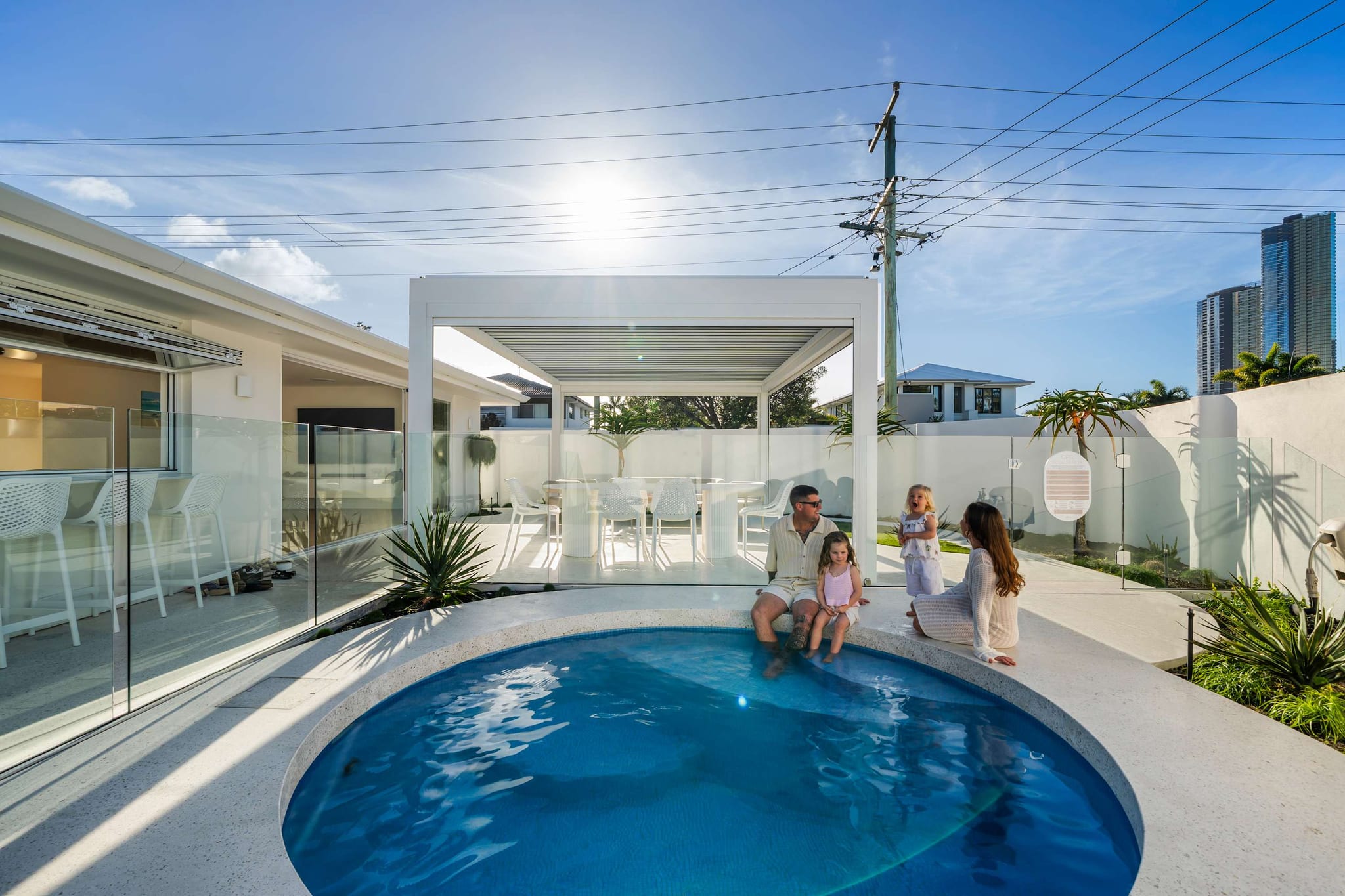 A family sitting on the edge of the round saltwater pool at The Pavilion, Mermaid Waters