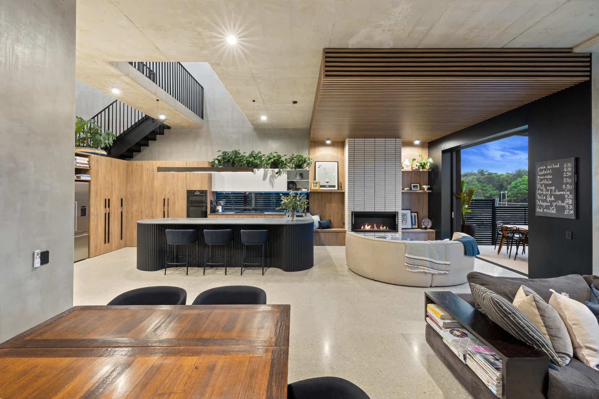 The open-plan kitchen and living space at Black on Black Wattle, with polished concrete floors and timber joinery