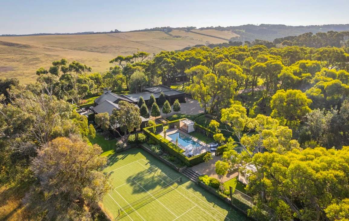 Musk Creek from above, a long dark house in bushland with a pool, lawn and rolling hills behind