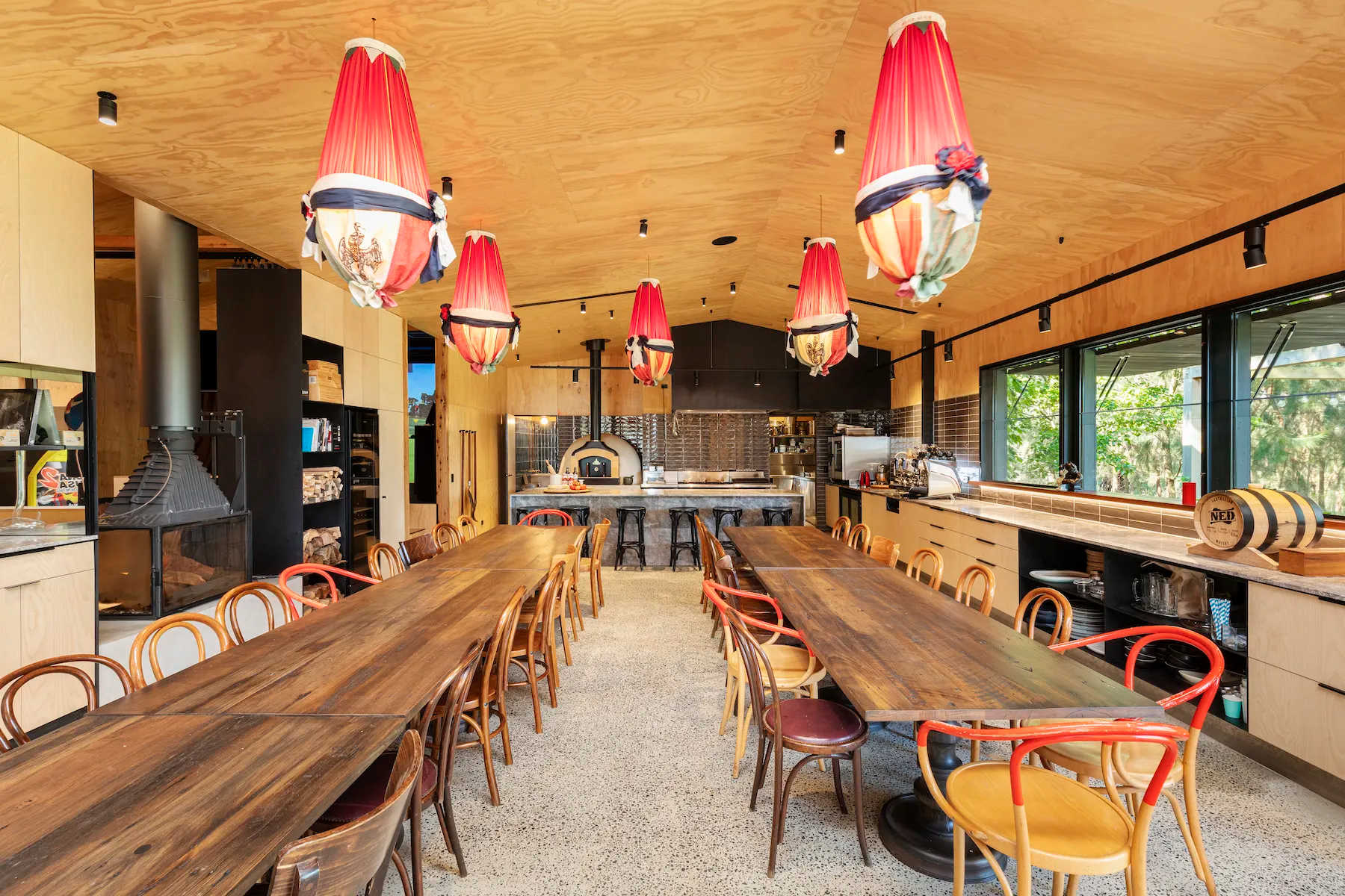 A long timber hall at Musk Creek with two long tables, bentwood chairs and red lanterns overhead