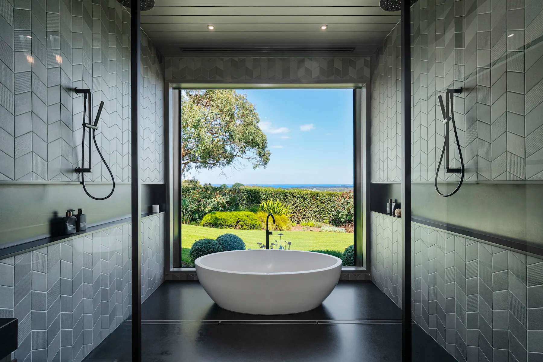 A freestanding bath in front of a big window looking over the garden to the horizon at Musk Creek