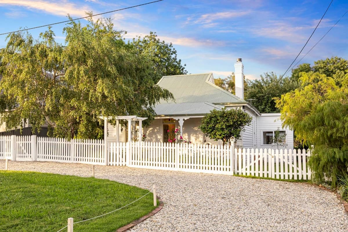 Oliver's Cottage behind a white picket fence under a blue evening sky